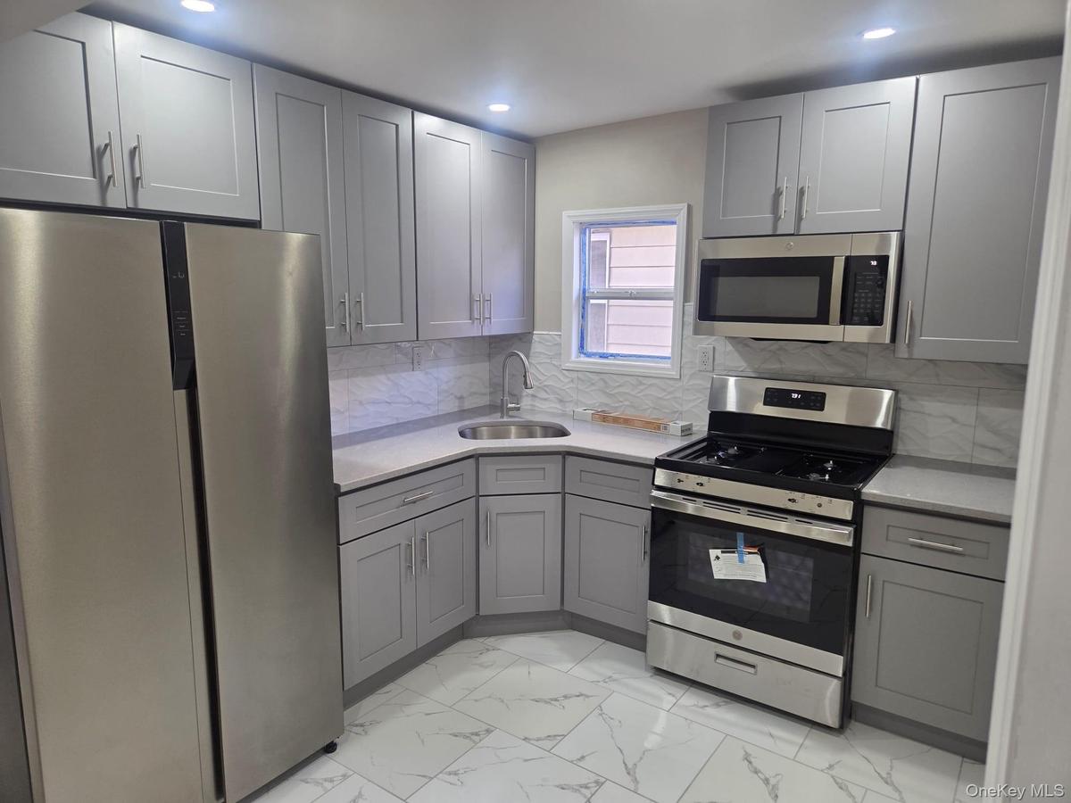 Second Floor Kitchen featuring stainless steel appliances, gray cabinetry, light tile finish flooring, and tasteful backsplash
