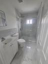 First Floor Bathroom featuring vanity, a tile finish shower, light tile finish flooring, and tile walls
