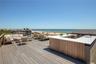 Deck with outdoor lounge area and view of water and beach