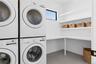 Washroom with stacked washer and clothes dryer and baseboards