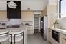 Kitchen featuring light brown cabinets, light stone counters, modern cabinets, and high quality fridge
