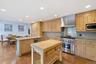 Kitchen featuring wood-finish cabinetry, stainless steel range with matching hood, integrated dishwasher, and a center island with a butcher block cou