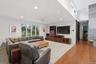Expansive living area with recessed lighting, large windows, wood-finish flooring, and a stone-clad architectural feature