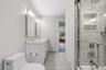 Dual vanity with stone countertop, modern bath lighting, tile flooring, glass shower enclosure, and integrated shower niche