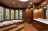 Jacuzzi tub with built-in steps, curved wall of windows, wood-finish flooring, recessed lighting, and a dual vanity with a light-toned countertop