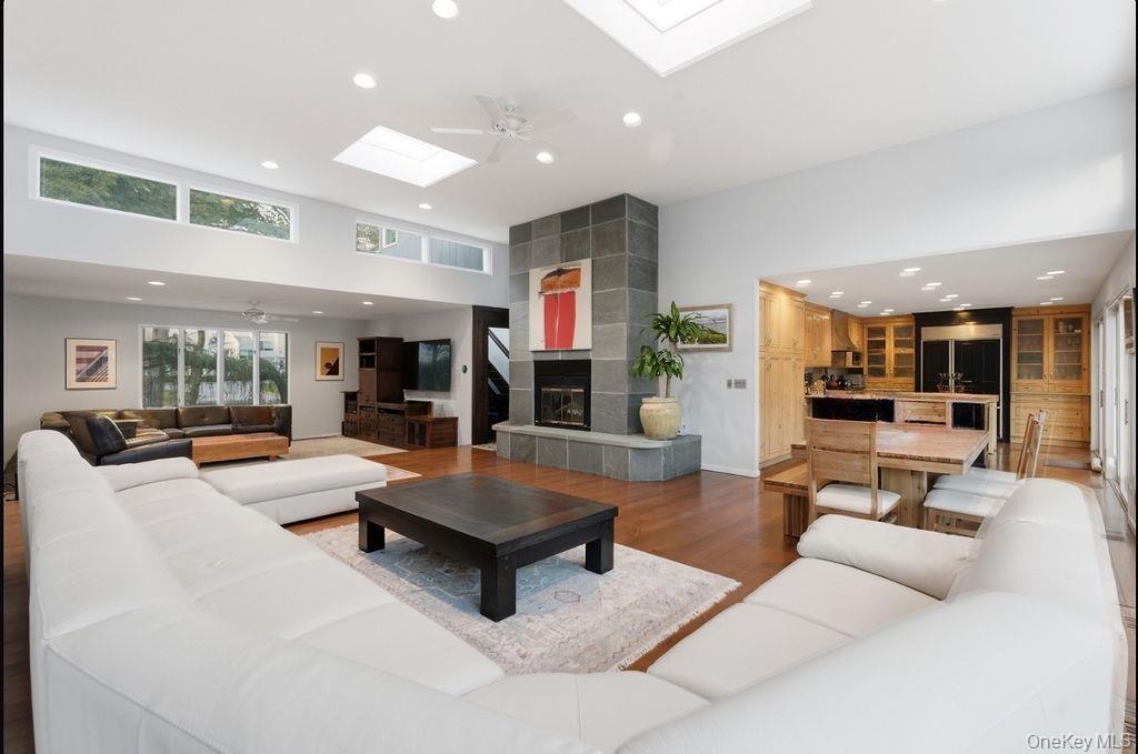 Spacious living area featuring high ceilings, wood-finish flooring, and multiple skylights
