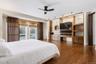 Wood-finish flooring with built-in entertainment center, ceiling fan, and sliding glass door with privacy screens