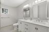 Dual vanity with integrated sinks and brushed nickel fixtures, white shaker cabinetry, large framed mirrors, and light-toned tile flooring