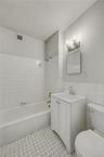 Bathroom with shower / tub combination, tile walls, and vanity