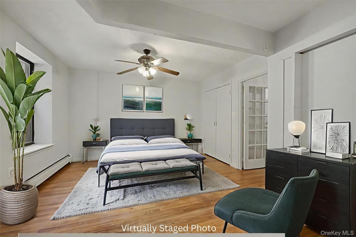 Bedroom with a baseboard radiator, wood finished floors, and a ceiling fan