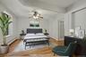 Bedroom with a baseboard radiator, wood finished floors, and a ceiling fan