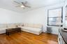 Living area with light wood-style floors, radiator, ceiling fan, and a healthy amount of sunlight