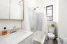 Bathroom featuring vanity, shower / bath combo, toilet, and tile walls