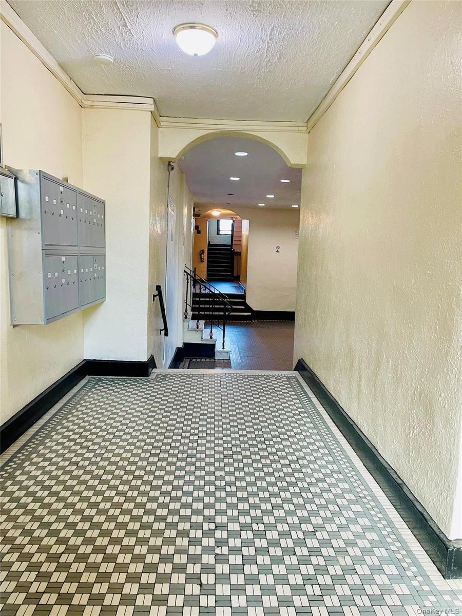 Hall featuring baseboards, mail area, a textured ceiling, ornamental molding, and arched walkways