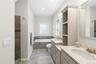 Full bath featuring two vanities, a bath, and exquisitely tiled shower