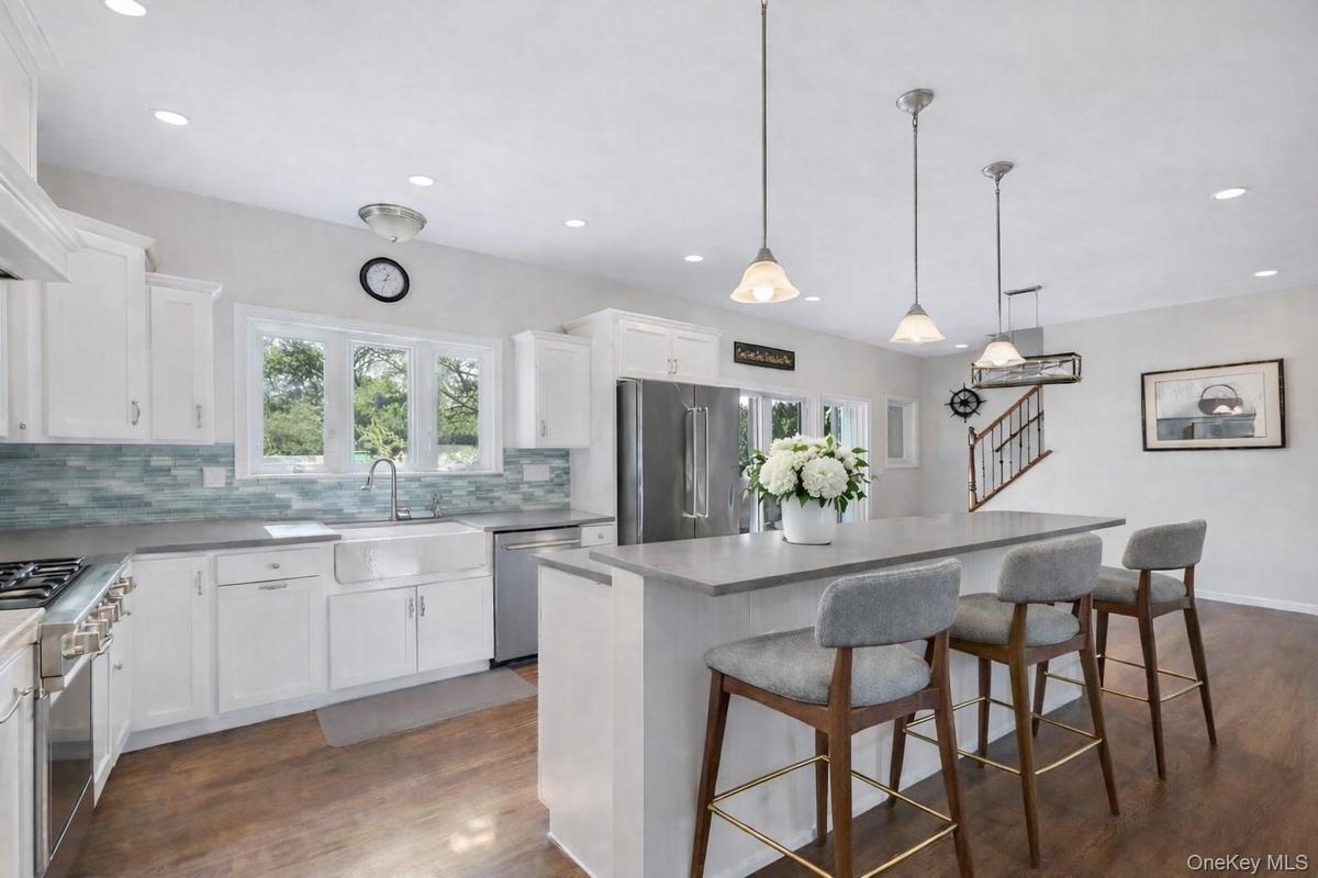 Kitchen featuring high quality appliances, a breakfast bar area, a kitchen island, and beautiful white cabinets