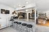 Kitchen featuring a kitchen bar, arched walkways, a peninsula, a baseboard radiator, and light stone counters