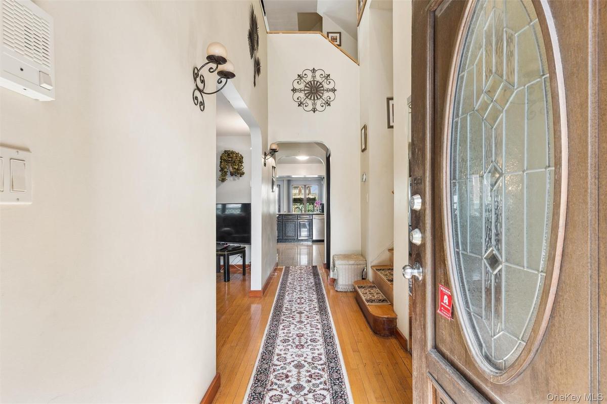 Foyer with arched walkways, a high ceiling, and light wood-type flooring