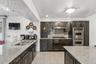 Kitchen featuring light stone countertops, dark finish cabinets, stainless steel appliances, granite floors, and recessed lighting