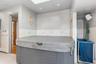 Master Bathroom Suite Detailed view of a hot tub, tile walls, a wainscoted wall, a skylight, and a baseboard radiator