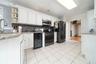 Kitchen featuring light stone counters, backsplash, gas stove, white cabinetry, and black fridge with ice dispenser