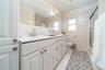 Full bath with tile walls, double vanity, light tile patterned floors, and enclosed tub / shower combo