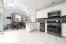 Kitchen with stainless steel appliances, a skylight, backsplash, wine cooler, and white cabinets