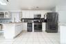 Kitchen with black fridge, light stone countertops, white cabinetry, gas stove, and open shelves