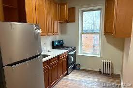 Kitchen featuring freestanding refrigerator, gas range, a healthy amount of sunlight, and radiator