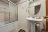 Bathroom featuring bath / shower combo with glass door and tile walls