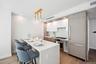 Kitchen featuring appliances with stainless steel finishes, a kitchen bar, modern cabinets, light wood-type flooring, and light countertops