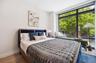 Bedroom with multiple windows, baseboards, wood finished floors, and expansive windows