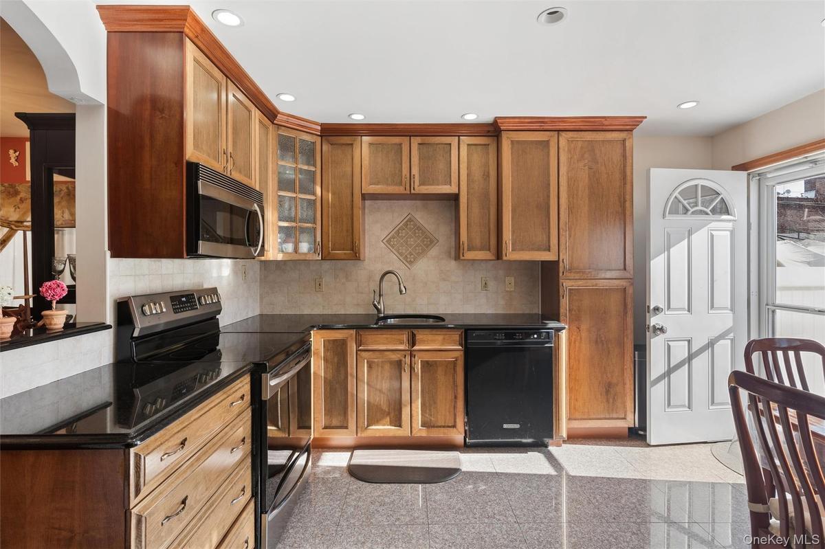 The kitchen is thoughtfully appointed with custom-made cabinetry, a convenient pull-out pots and pans shelves and sleek granite countertops and floori