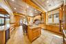Kitchen with a breakfast bar, ornamental molding, light stone counters, tasteful backsplash, and glass insert cabinets