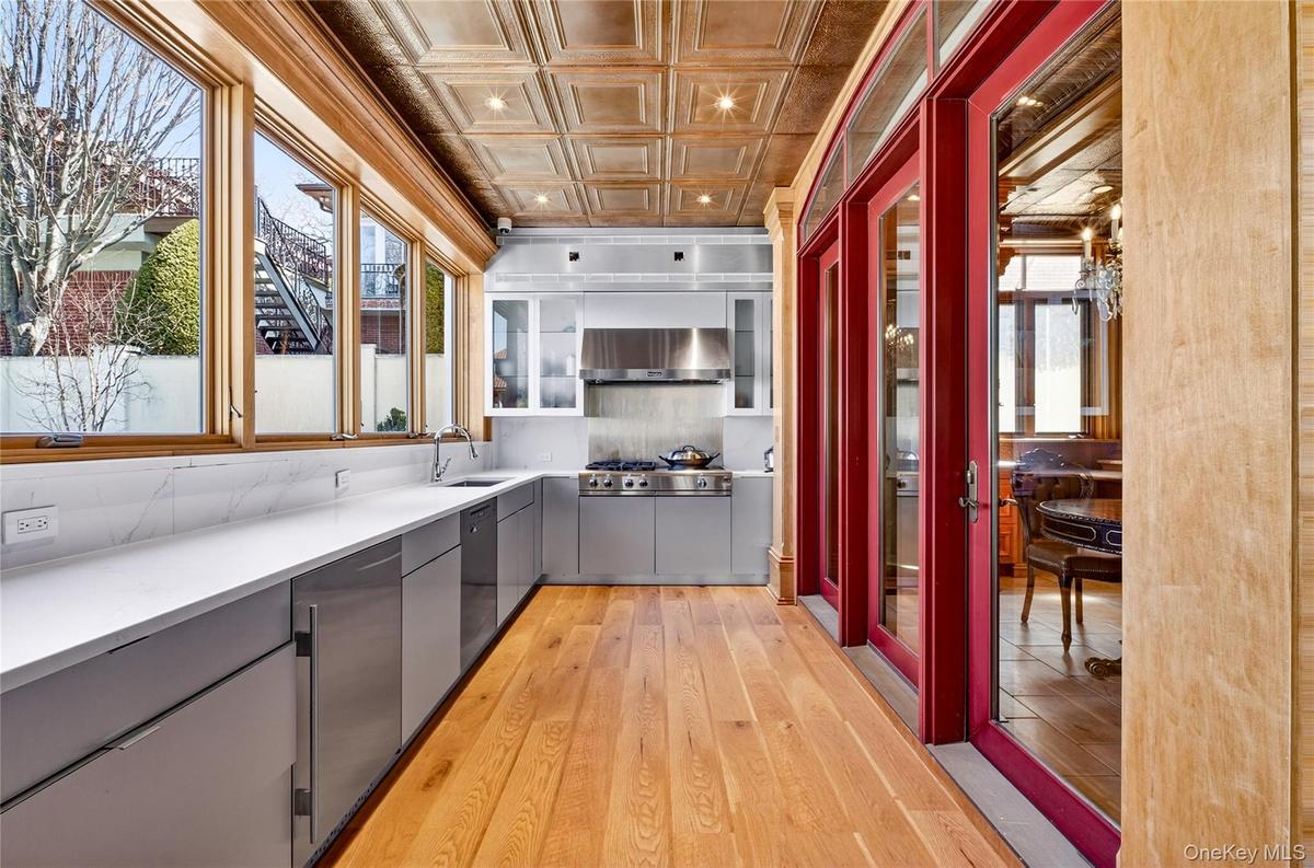 Kitchen featuring gray cabinetry, light wood-type flooring, light countertops, an ornate ceiling, and decorative backsplash