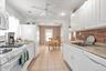 Kitchen featuring white appliances, white cabinetry, light countertops, decorative backsplash, and light tile patterned flooring