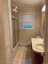 Bathroom with vanity, light tile patterned flooring, shower / bath combination with glass door, a closet, and baseboard heating