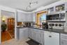 Kitchen with white dishwasher, dark countertops, stainless steel microwave, tasteful backsplash, and crown molding