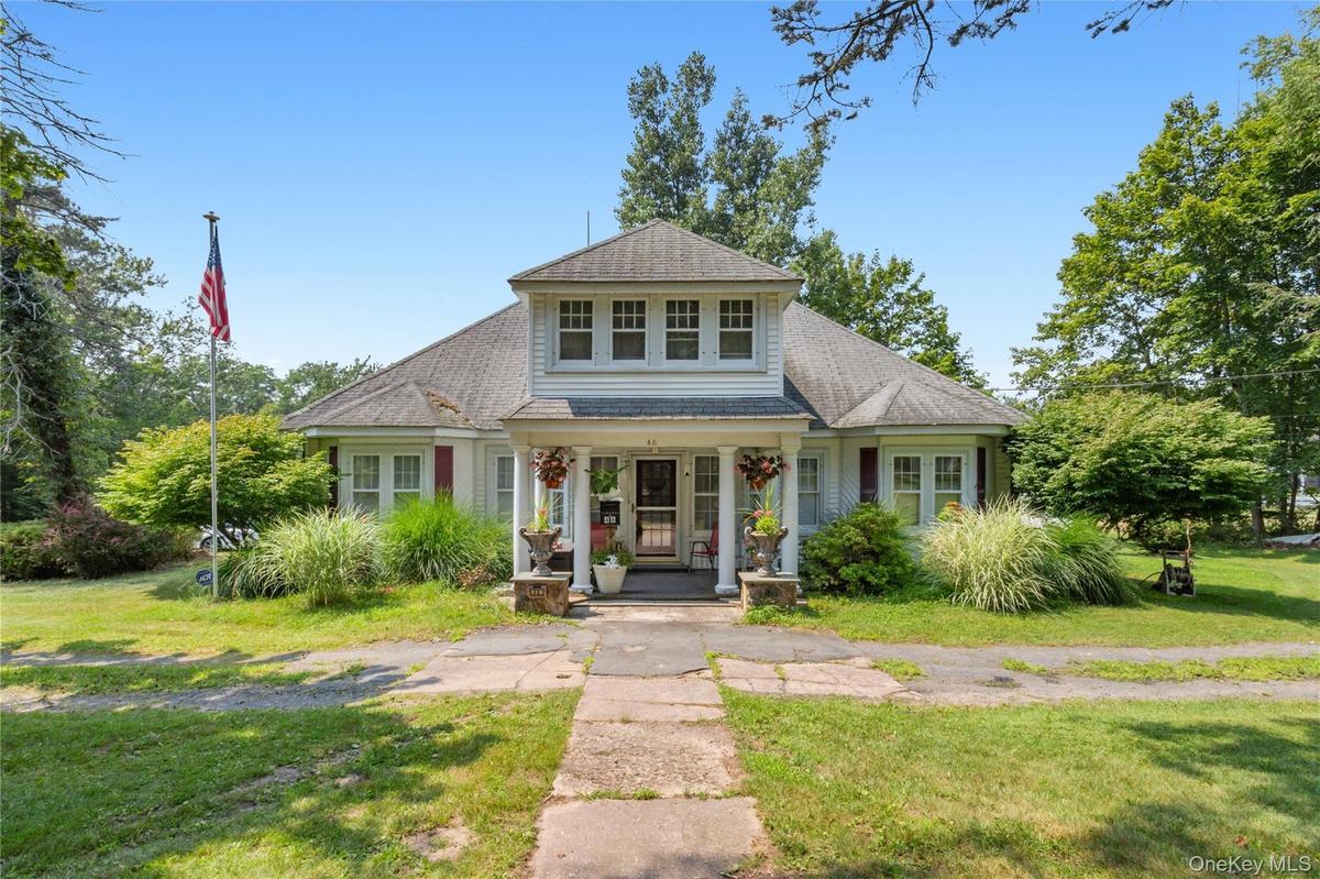 View of front of home with a porch, a shingled roof, and a front yard