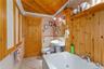 Bathroom featuring wallpapered walls, wainscoting, a whirlpool tub, tile patterned floors, and ornamental molding