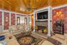 Tiled living room featuring wallpapered walls, wooden ceiling, radiator, a fireplace, and a ceiling fan