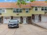 Townhome / multi-family property featuring roof with shingles, driveway, brick siding, an attached garage, and cooling unit