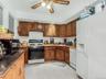 Apt 2 - Kitchen featuring white appliances, ceiling fan, light tile patterned floors, and brown cabinetry