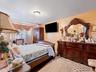 This room features a bed with a wooden frame, hardwood floors, and a ceiling-mounted light fixture