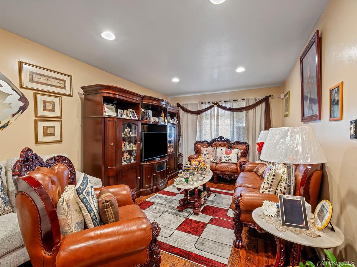 Living area featuring recessed lighting, light-colored walls, and hardwood flooring visible beneath a patterned rug