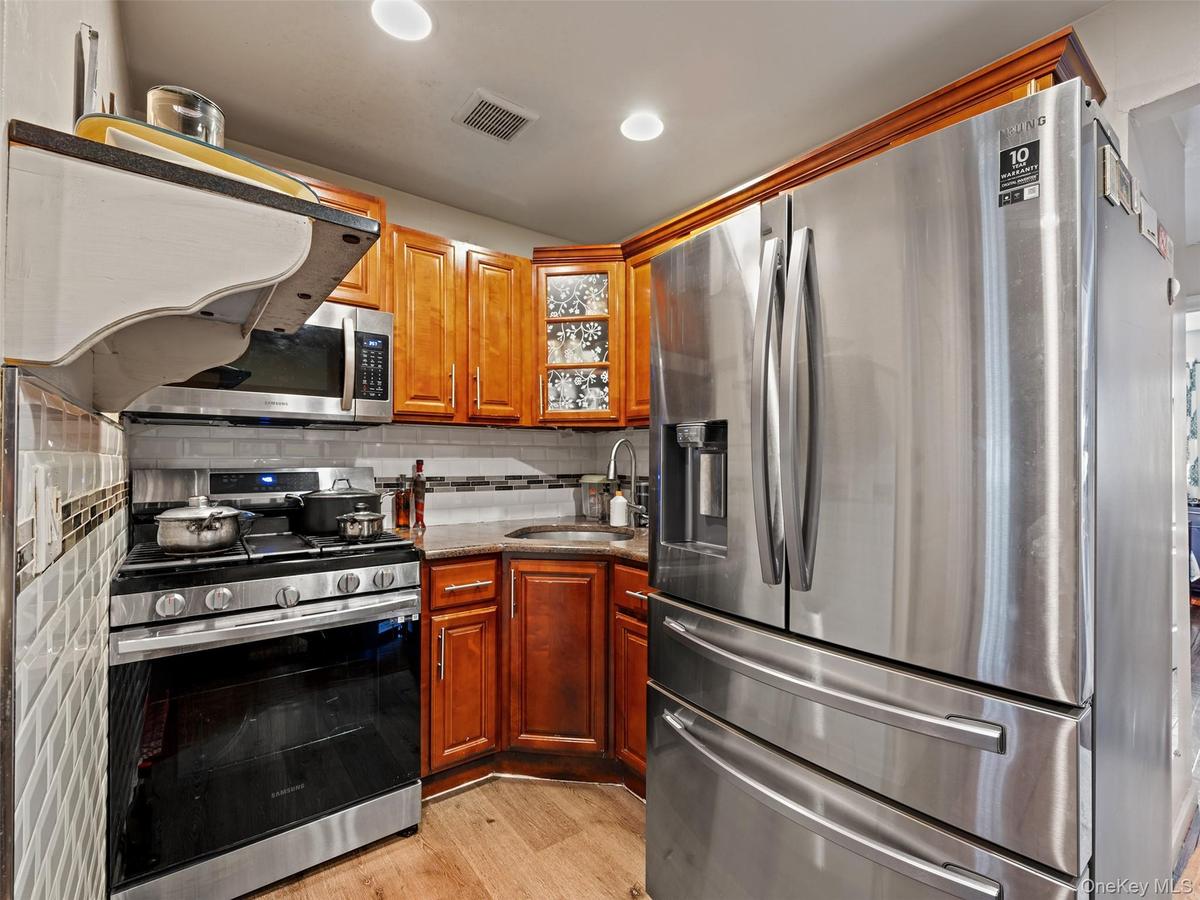 The kitchen features stainless steel appliances, including a refrigerator, microwave, and range