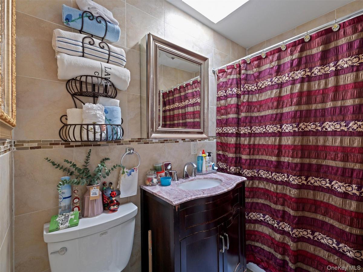 The bathroom features a vanity with a countertop and a mirror, complemented by tiled walls with a decorative border