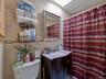 The bathroom features a vanity with a countertop and a mirror, complemented by tiled walls with a decorative border