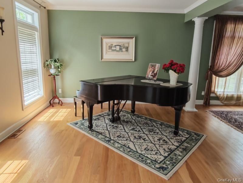 oak wood finished floors, crown molding, and decorative columns