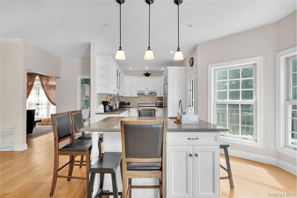 Kitchen with a breakfast bar area, white cabinets, dark stone countertops, backsplash, and recessed lighting